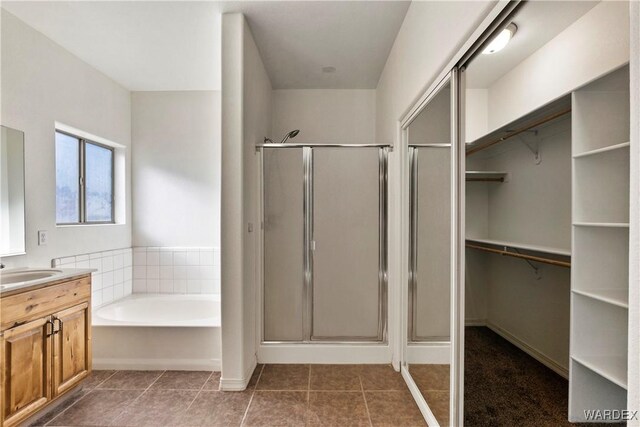 bathroom with tile patterned floors, a garden tub, a spacious closet, vanity, and a shower stall