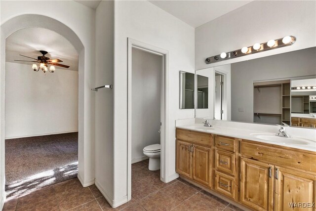 bathroom with a ceiling fan, a sink, toilet, and double vanity