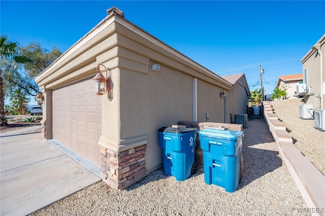 view of property exterior featuring an outbuilding, concrete driveway, an attached garage, and stucco siding