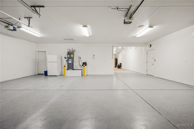 garage with water heater, a garage door opener, and freestanding refrigerator