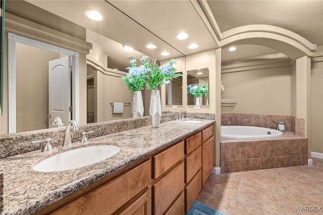 bathroom featuring double vanity, a sink, a bath, and tile patterned floors