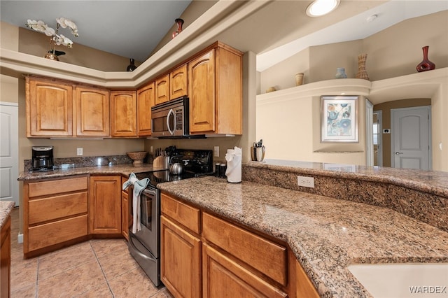 kitchen featuring lofted ceiling, appliances with stainless steel finishes, brown cabinets, and light stone countertops