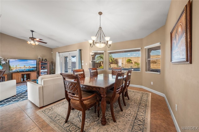 tiled dining area featuring ceiling fan with notable chandelier, baseboards, vaulted ceiling, and french doors