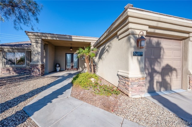 exterior space featuring an attached garage, stone siding, and stucco siding