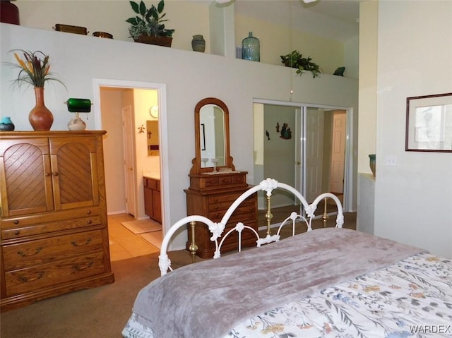 bedroom featuring light colored carpet, a towering ceiling, and ensuite bathroom