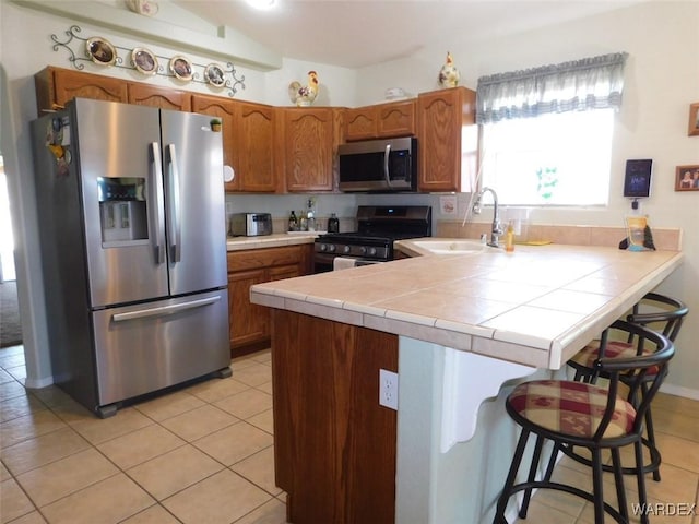 kitchen with stainless steel appliances, a breakfast bar area, a peninsula, and brown cabinets