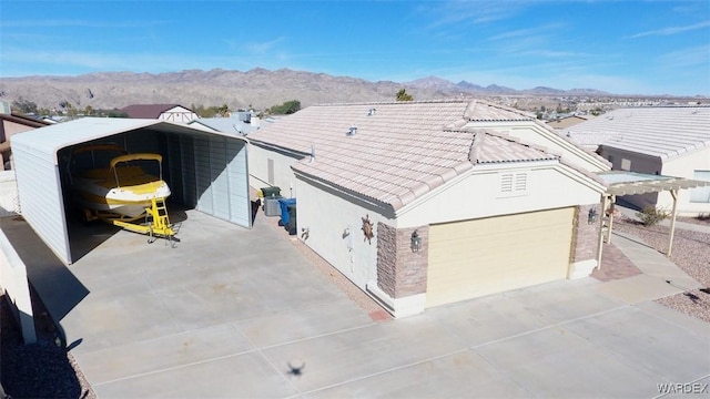 ranch-style home featuring a mountain view, concrete driveway, a tiled roof, stucco siding, and a carport