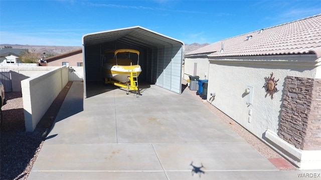 exterior space with driveway, fence, and a detached carport