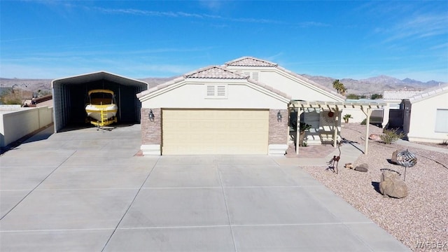 view of front facade featuring a tile roof, stucco siding, concrete driveway, an attached garage, and a mountain view