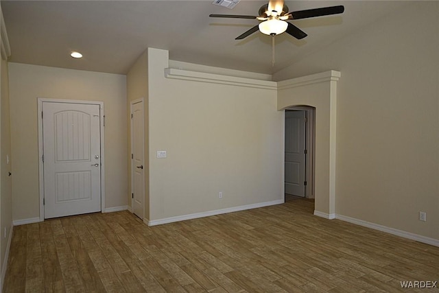 unfurnished room with visible vents, a ceiling fan, arched walkways, and wood finished floors