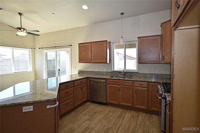 kitchen with appliances with stainless steel finishes, brown cabinets, a sink, and a peninsula