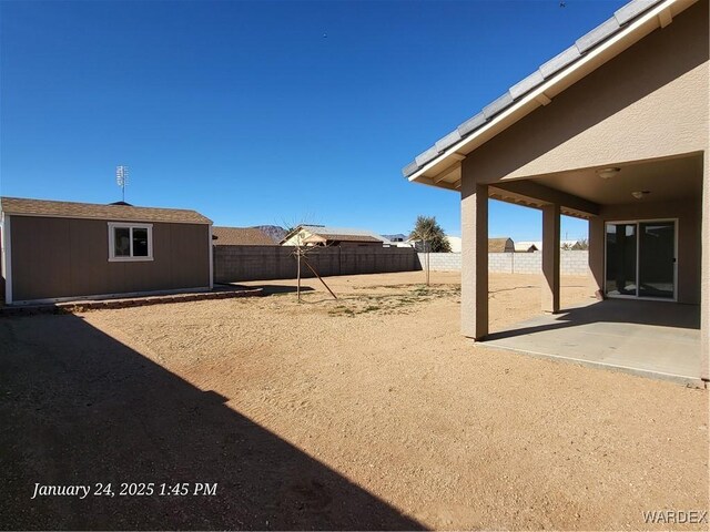 view of yard with an outbuilding, a patio area, a fenced backyard, and a storage unit