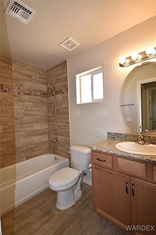 bathroom with toilet, wood finished floors, and visible vents