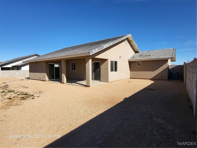 rear view of house with a tile roof, fence, a patio, and stucco siding