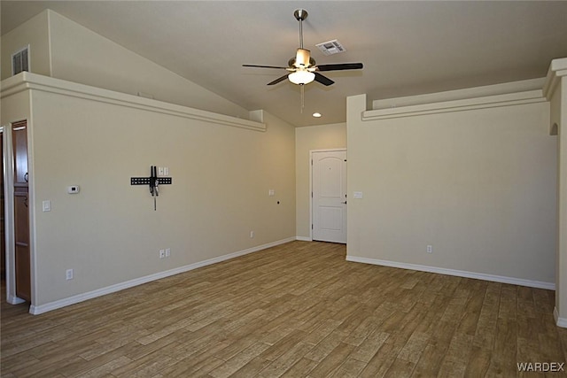 empty room featuring lofted ceiling, visible vents, and wood finished floors