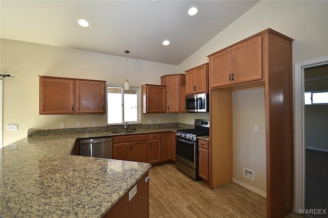 kitchen with decorative light fixtures, appliances with stainless steel finishes, light wood-style floors, brown cabinetry, and a sink