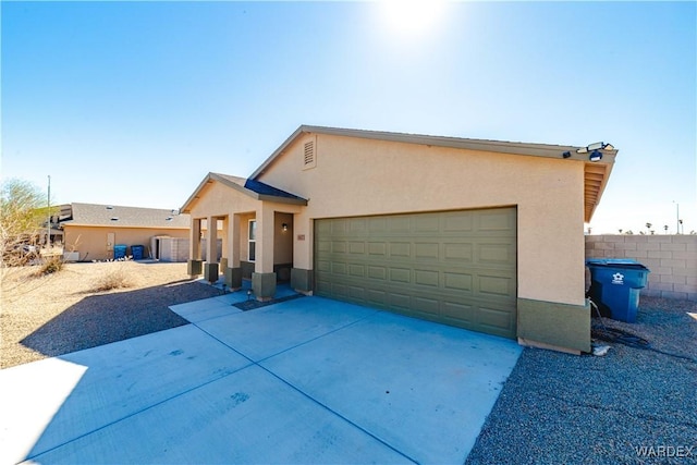 view of front of property with driveway, fence, an attached garage, and stucco siding