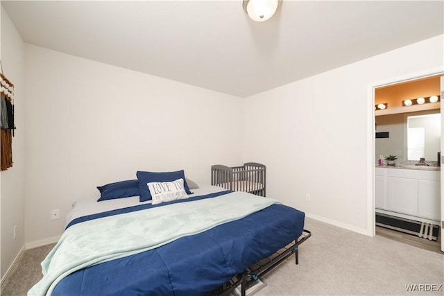 bedroom featuring light carpet, baseboards, and ensuite bathroom