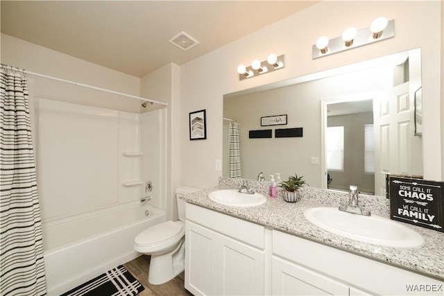 bathroom featuring toilet, double vanity, visible vents, and a sink