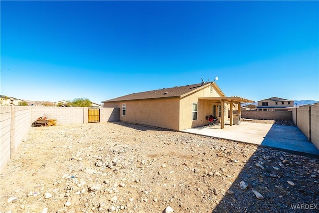 rear view of property featuring a patio area, a fenced backyard, a gate, and stucco siding