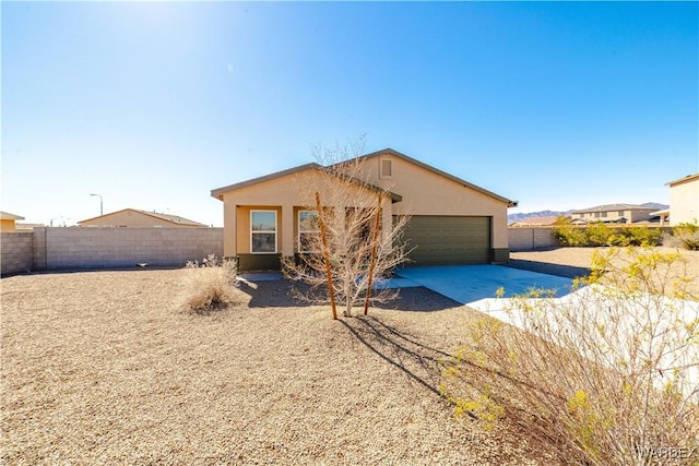 rear view of house featuring driveway, fence, an attached garage, and stucco siding