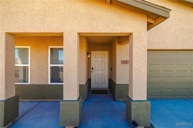 entrance to property with a garage and stucco siding