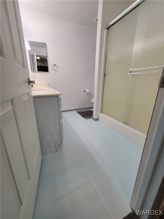 full bathroom featuring toilet, a shower stall, vanity, and baseboards