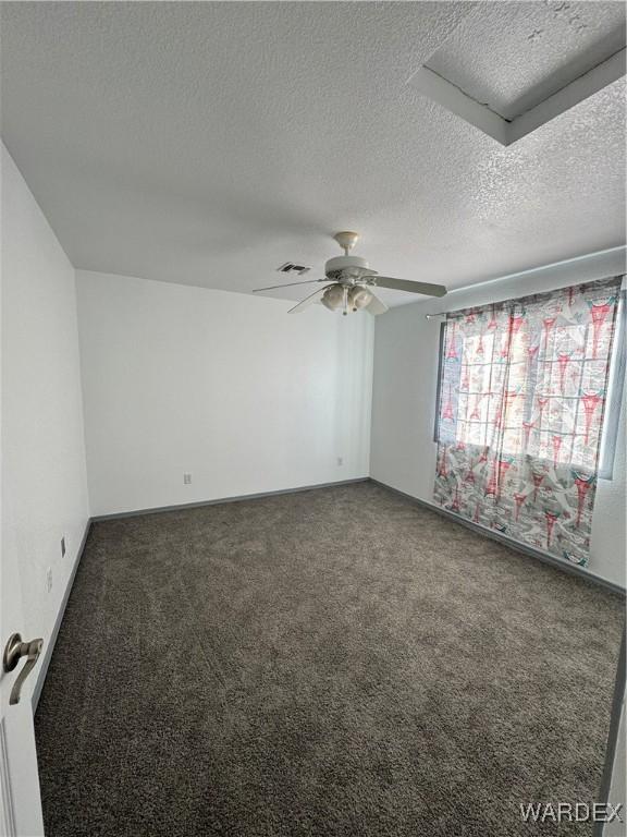 empty room with ceiling fan, visible vents, dark colored carpet, and a textured ceiling