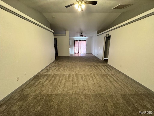 spare room with ceiling fan, visible vents, dark carpet, and vaulted ceiling