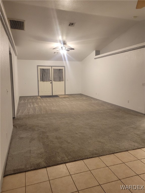 empty room featuring lofted ceiling, visible vents, light carpet, and light tile patterned flooring