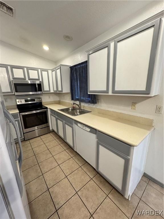 kitchen featuring light tile patterned flooring, stainless steel appliances, a sink, visible vents, and light countertops