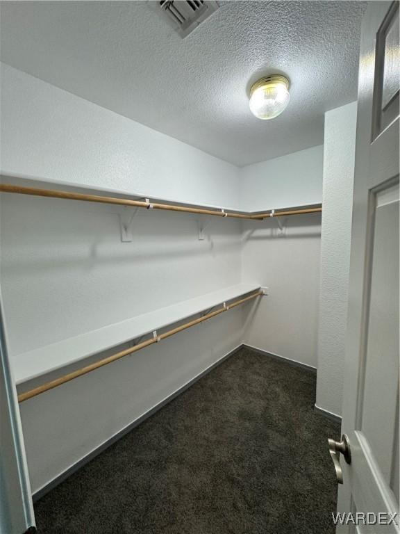 walk in closet with visible vents and dark carpet