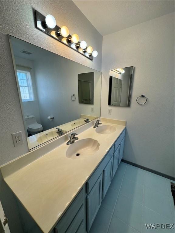 full bath featuring toilet, double vanity, and a sink