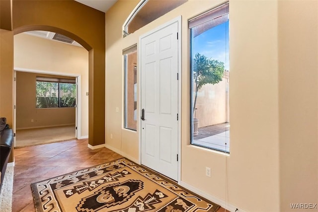 tiled foyer with baseboards and arched walkways