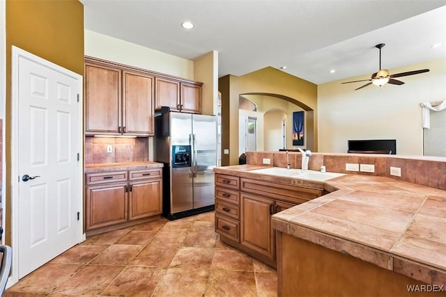 kitchen featuring tasteful backsplash, a sink, brown cabinets, and stainless steel fridge with ice dispenser