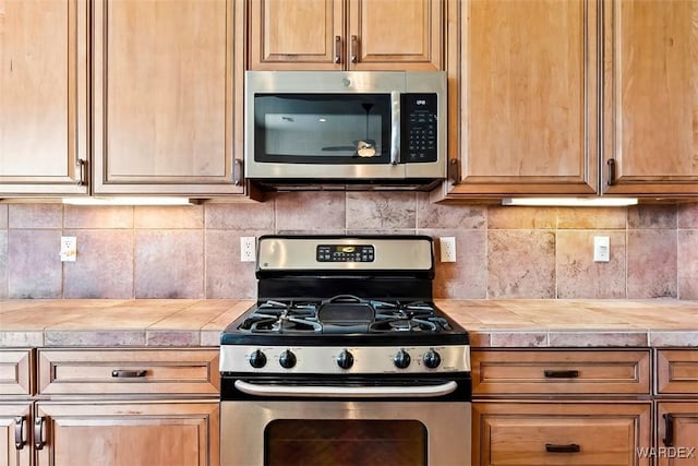 kitchen with stainless steel appliances, tasteful backsplash, and light countertops