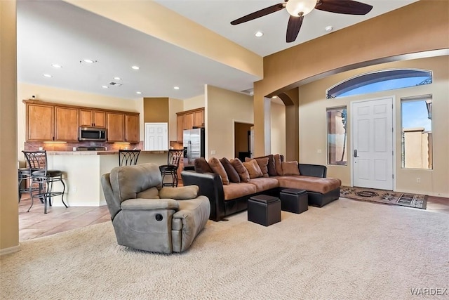 living room with arched walkways, recessed lighting, light colored carpet, and a ceiling fan