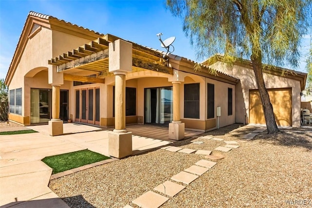 rear view of house featuring stucco siding and a patio area