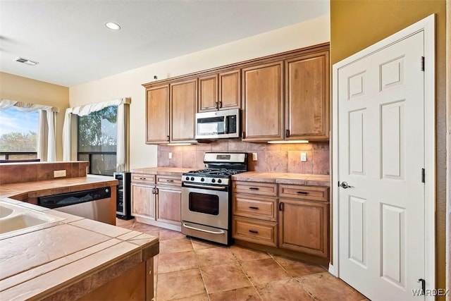 kitchen with visible vents, beverage cooler, backsplash, stainless steel appliances, and light tile patterned floors