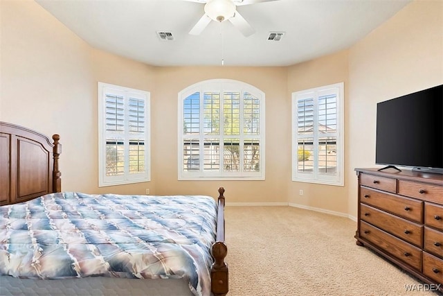 bedroom featuring visible vents, light colored carpet, a ceiling fan, and baseboards