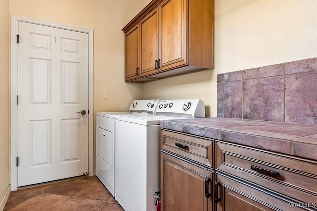 washroom featuring cabinet space, light tile patterned floors, and independent washer and dryer