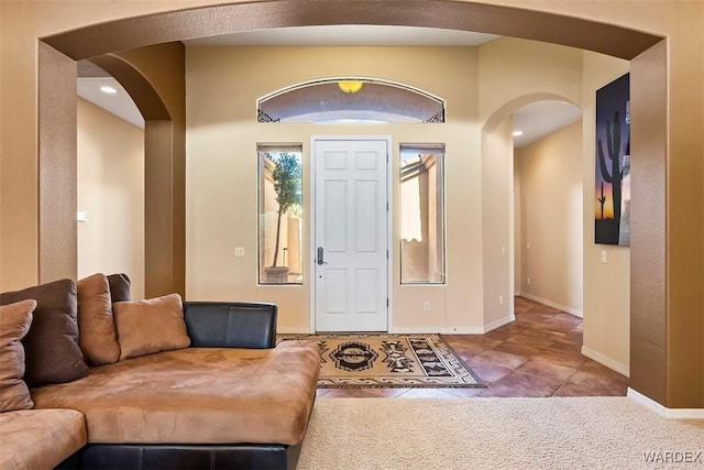 tiled foyer featuring baseboards and arched walkways