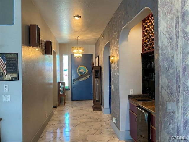 211 Columbine Dr, Lake Havasu, AZ 86403 - hall with a sink, marble finish floor, baseboards, arched walkways, and a notable chandelier