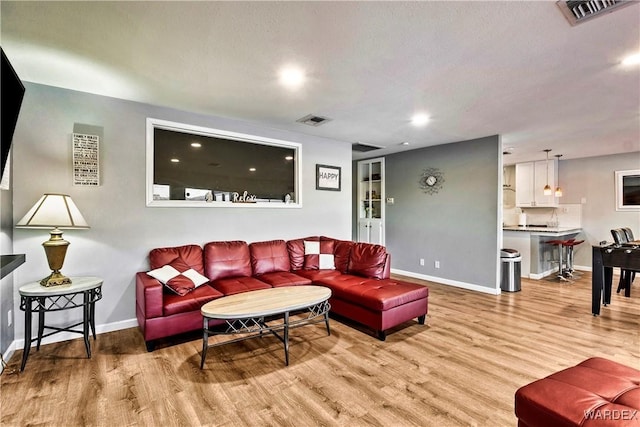 living area with light wood finished floors, baseboards, and visible vents