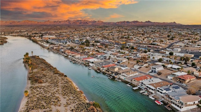 aerial view at dusk featuring a view of the beach, a residential view, and a water view