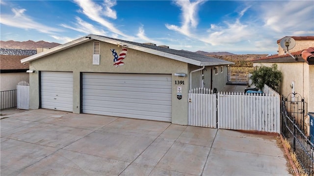 exterior space featuring driveway, fence, a mountain view, and stucco siding