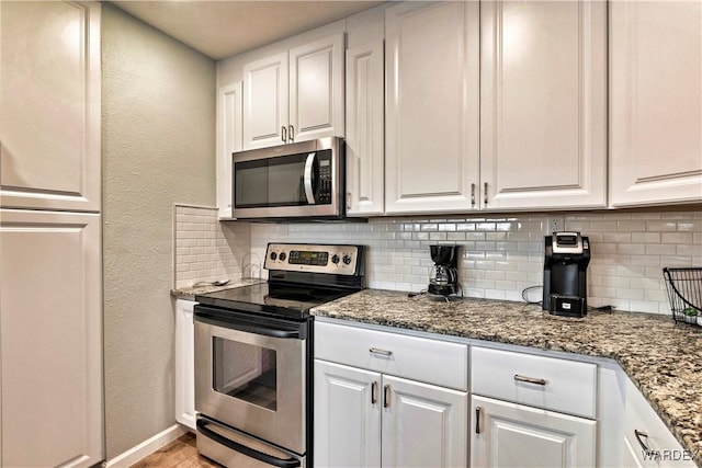 kitchen featuring stainless steel appliances, white cabinetry, and backsplash