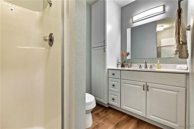 full bathroom with vanity, a shower, wood finished floors, and toilet