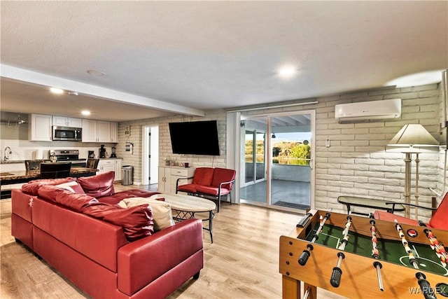 living area with a textured ceiling, brick wall, a wall mounted air conditioner, and light wood-style flooring