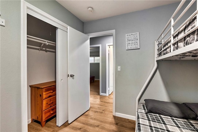 bedroom with a closet, light wood-type flooring, and baseboards